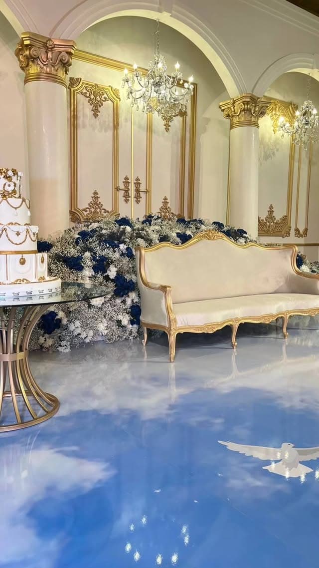 Tiered gold-trimmed wedding cake in an opulent gold-columned room