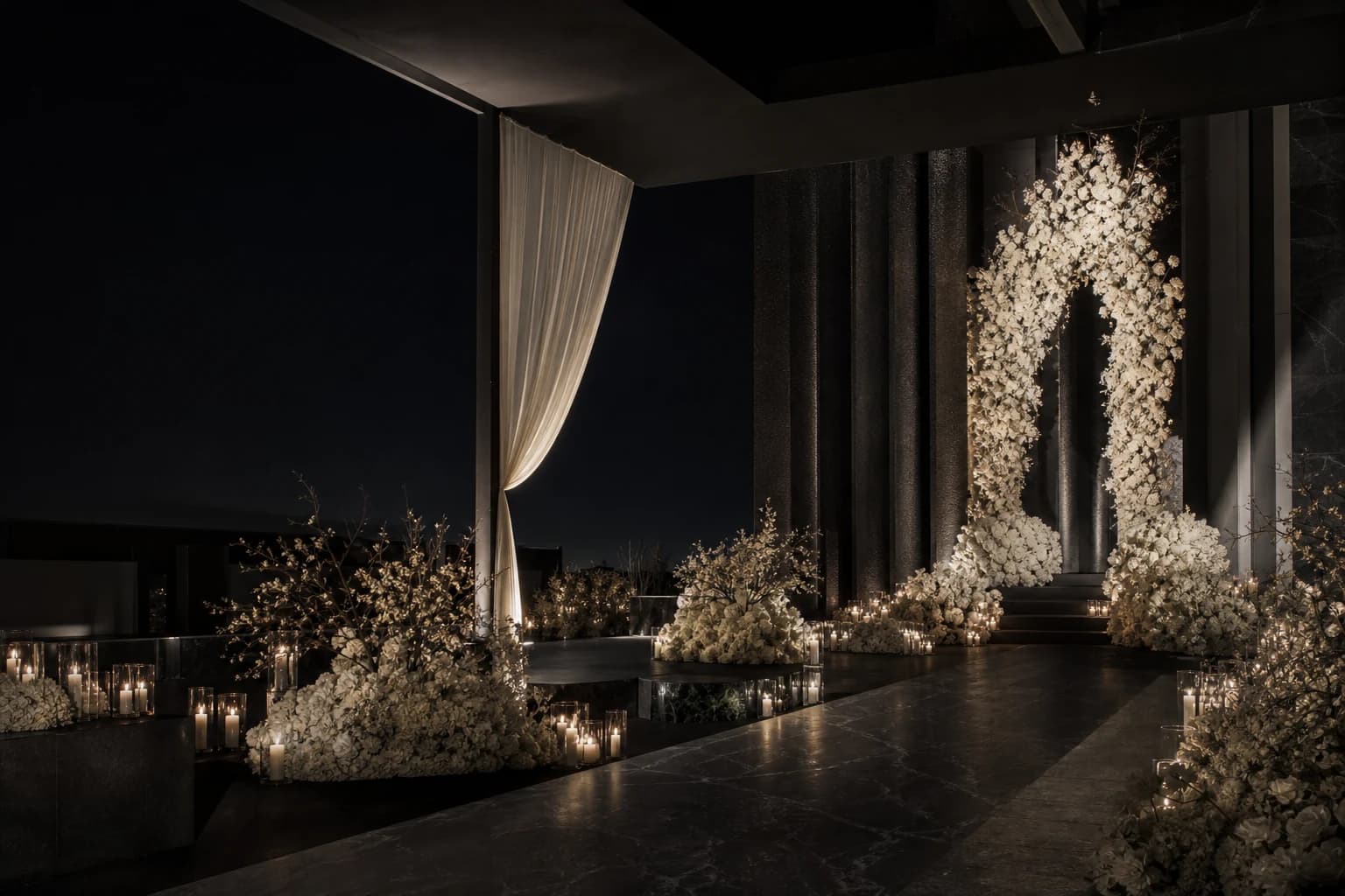 Black wedding pavilion with sculptural white florals and candlelit aisle
