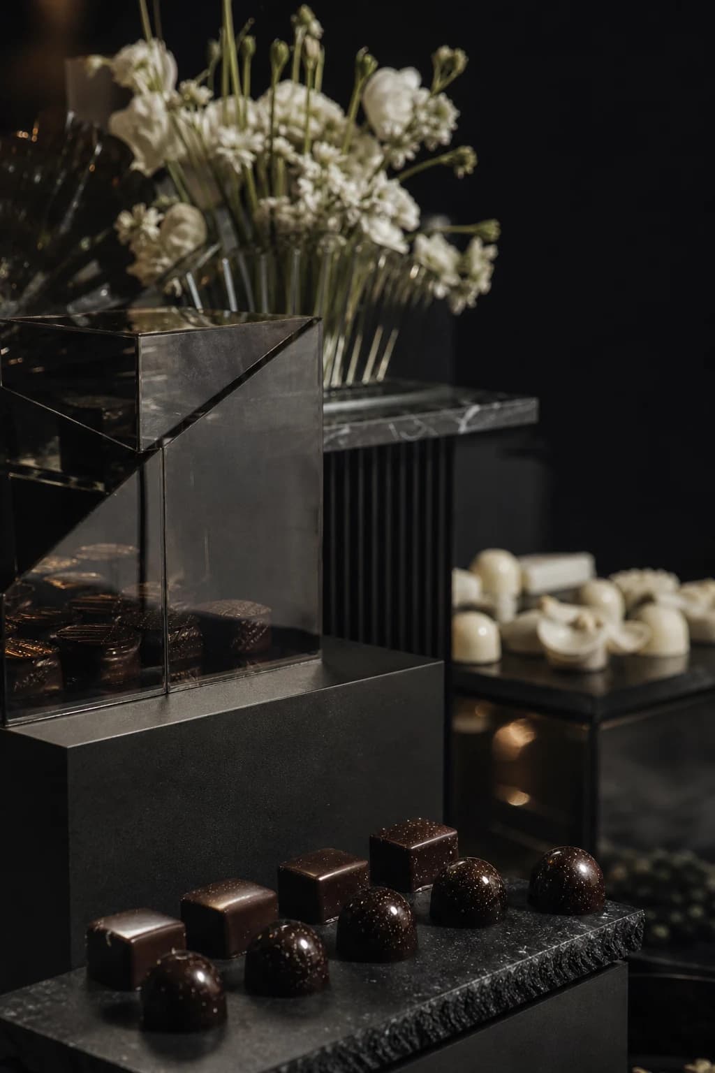 Architectural black chocolate display with ivory confections and white flowers