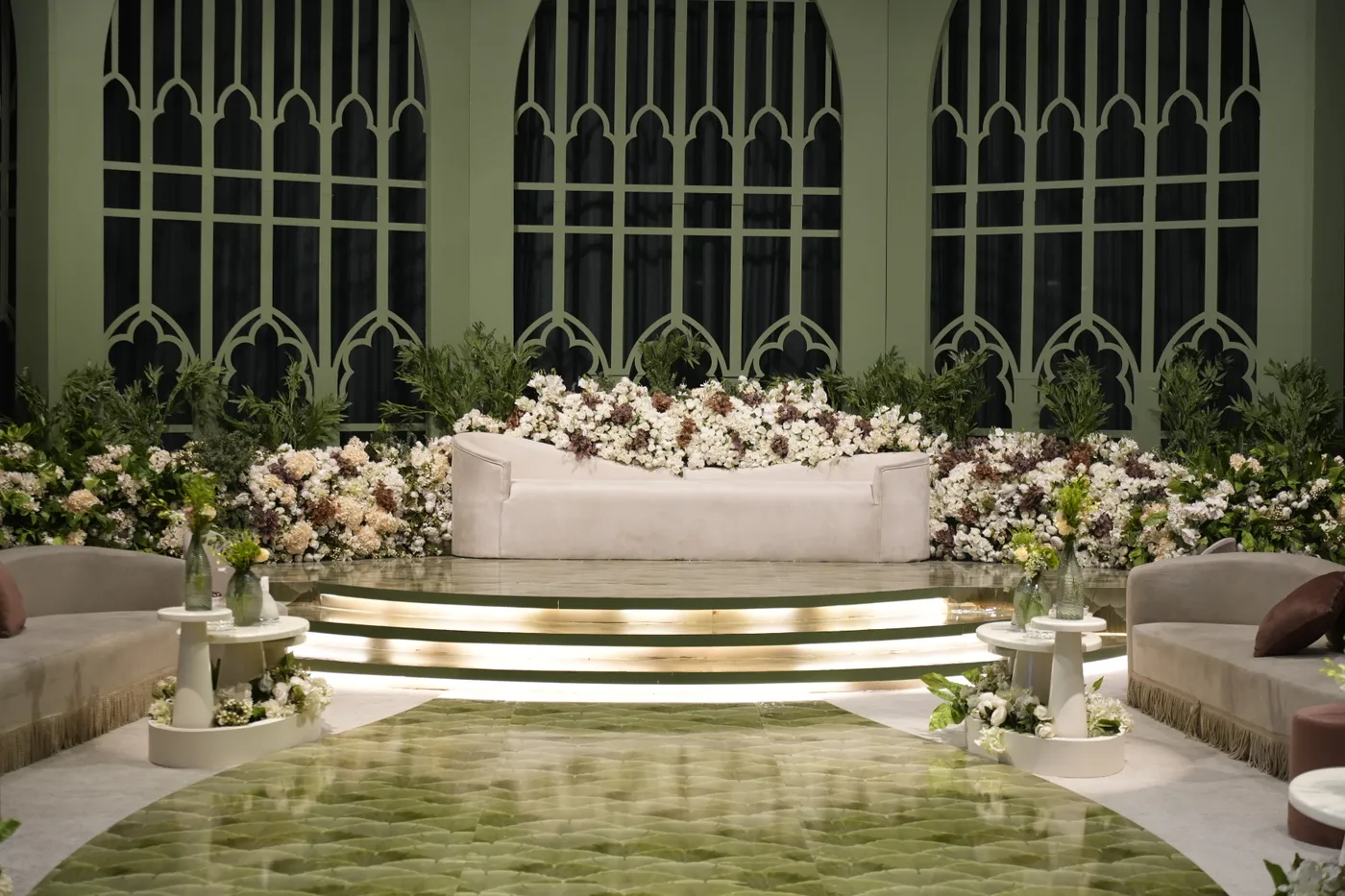 Blush floral arch wedding stage with soft romantic lighting